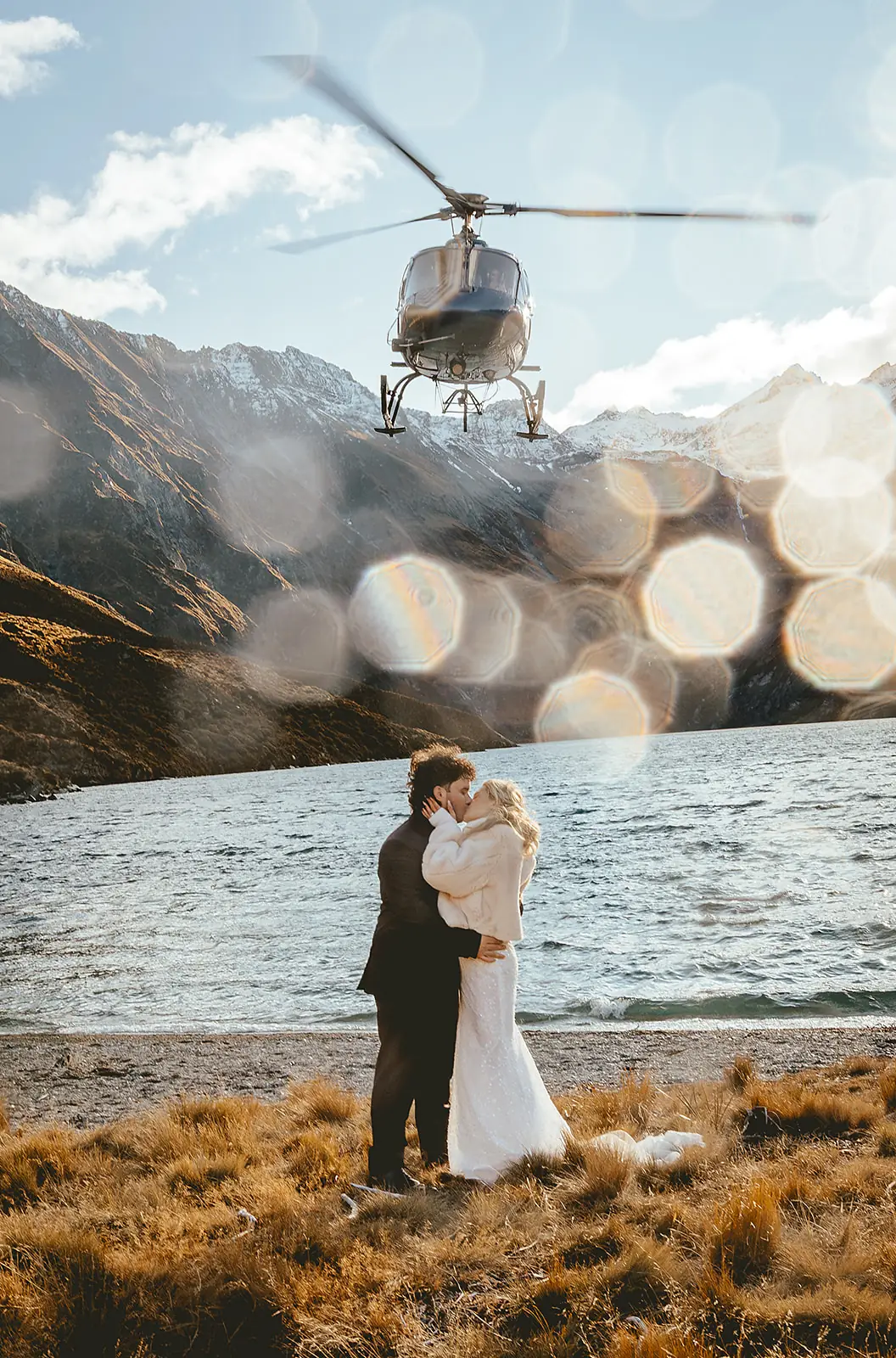 Helicopter flying past a couple kissing beside the alpine lake at Lochnagar