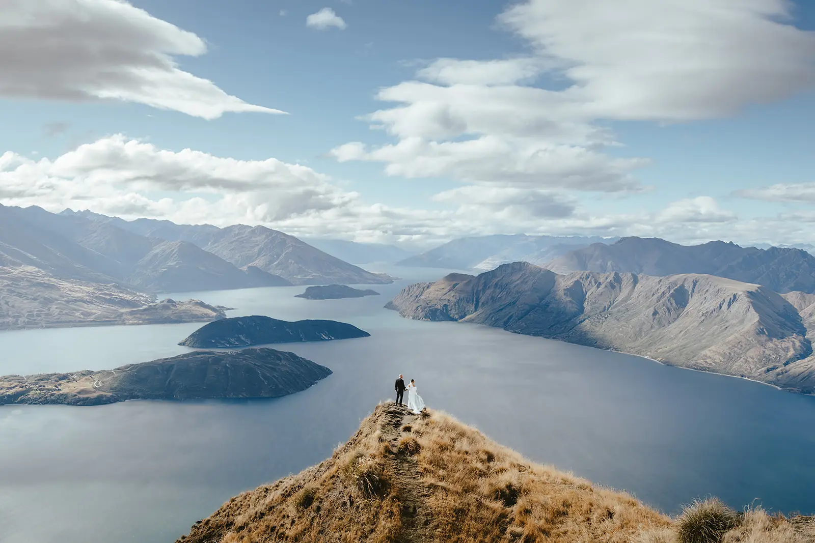 Bride and groom on the Coromandel Peak ridgeline high above Lake Wanaka and its islands