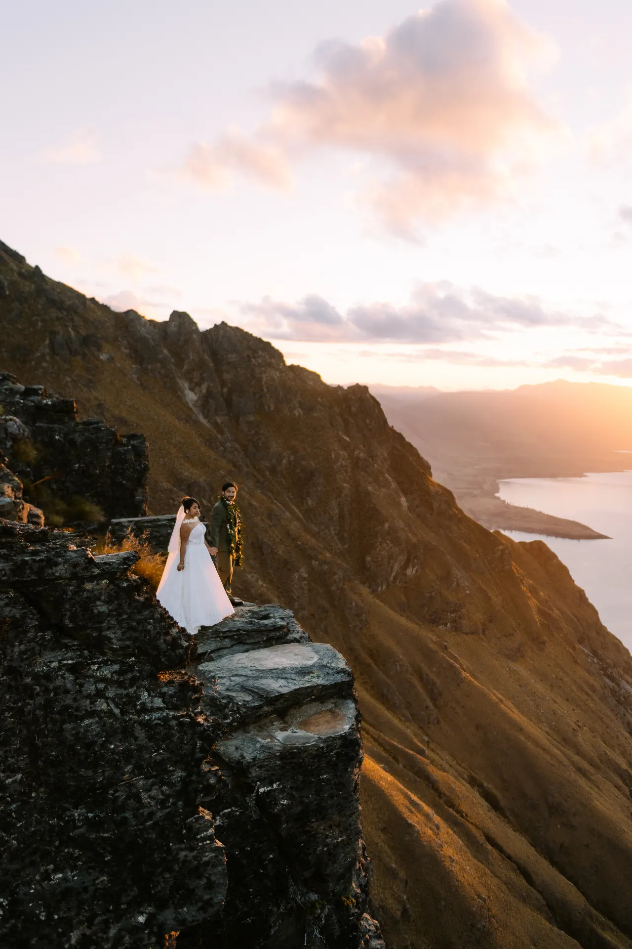 Couple on a cliff at Cecil Peak above Lake Wakatipu at sunset
