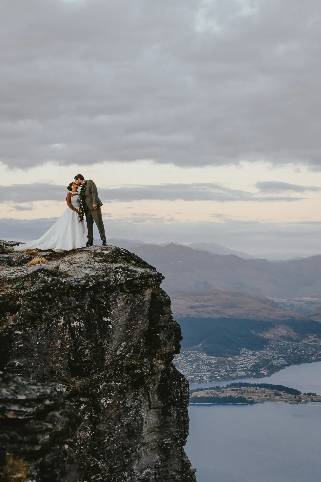 Couple kissing on a cliff edge with the Remarkables range behind them