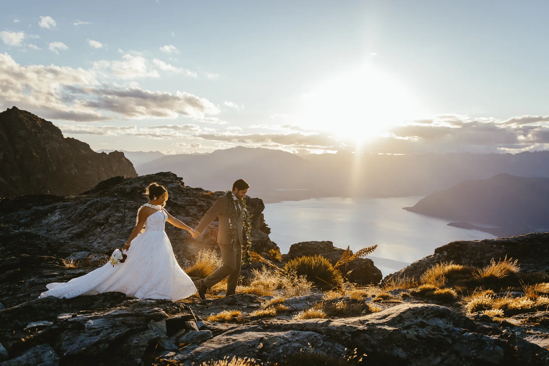 Couple walking along a ridge above Lake Wakatipu at sunset after a Queenstown elopement ceremony