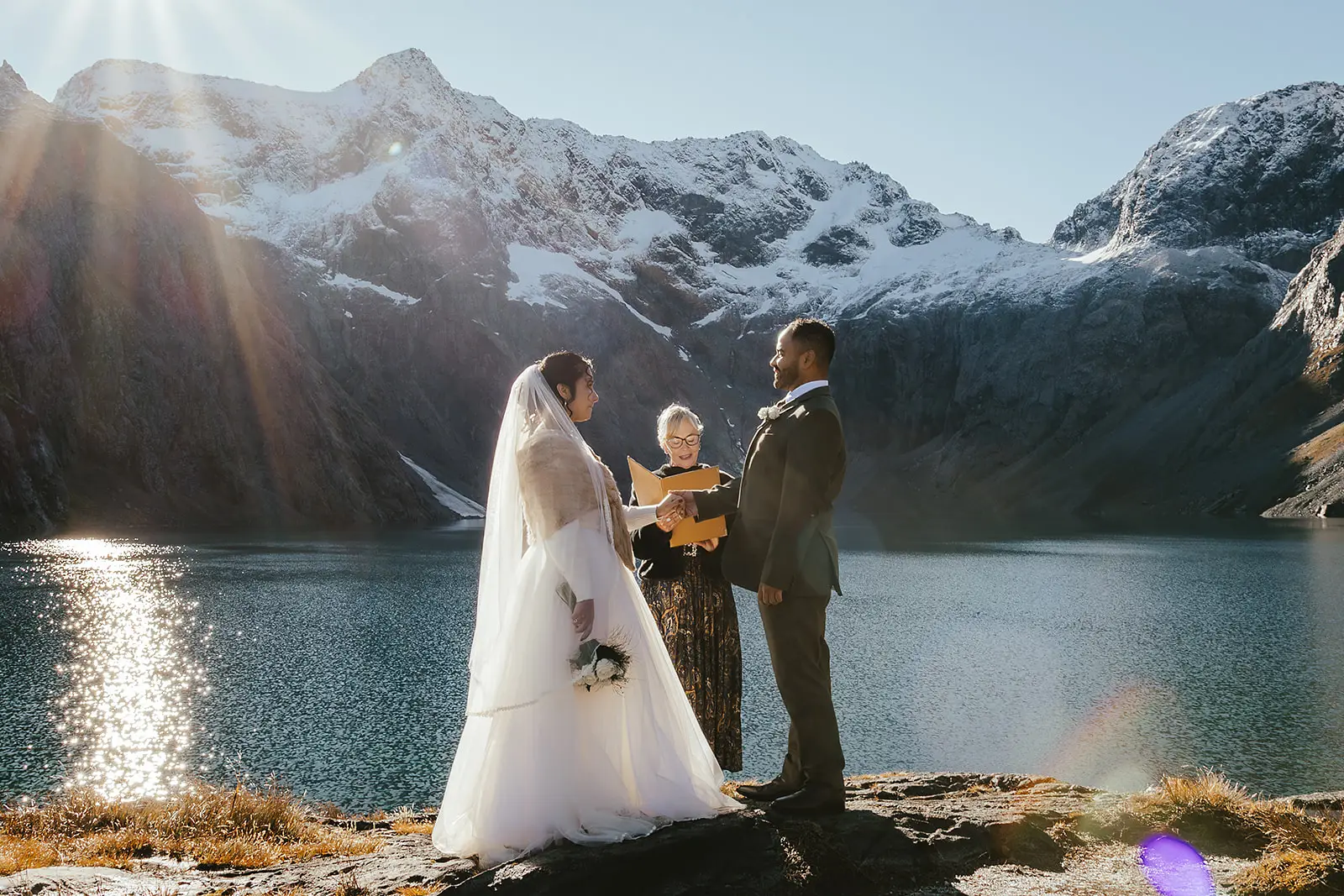 Couple and celebrant during a ceremony beside an alpine lake near Queenstown