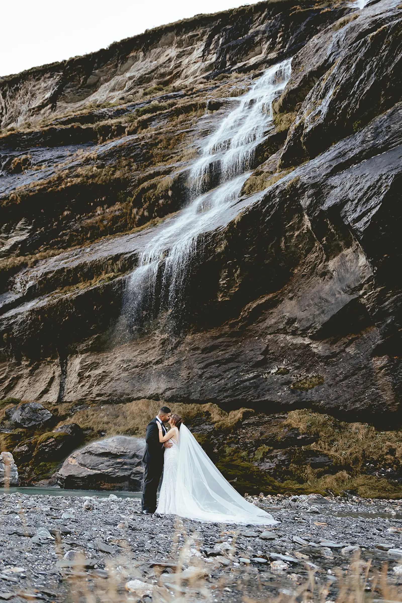 Couple kissing beneath the waterfalls at Earnslaw Burn after a helicopter landing